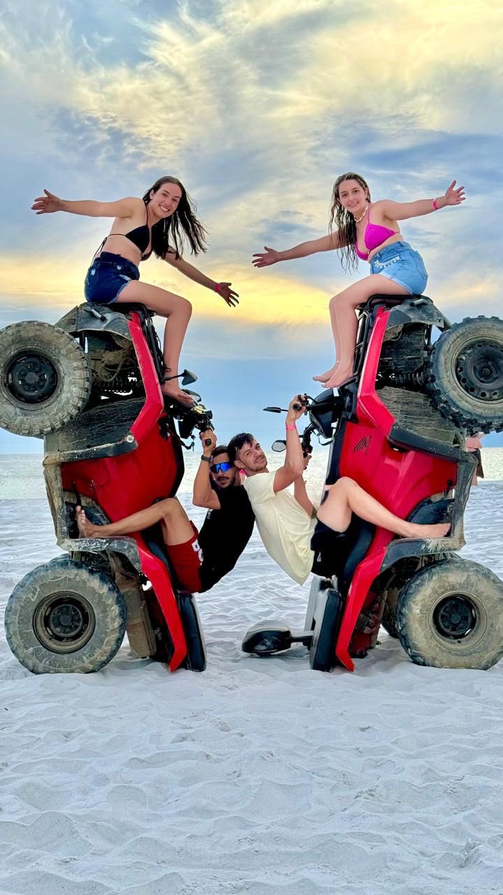 Amigos posando com quadriciclos em pé na praia